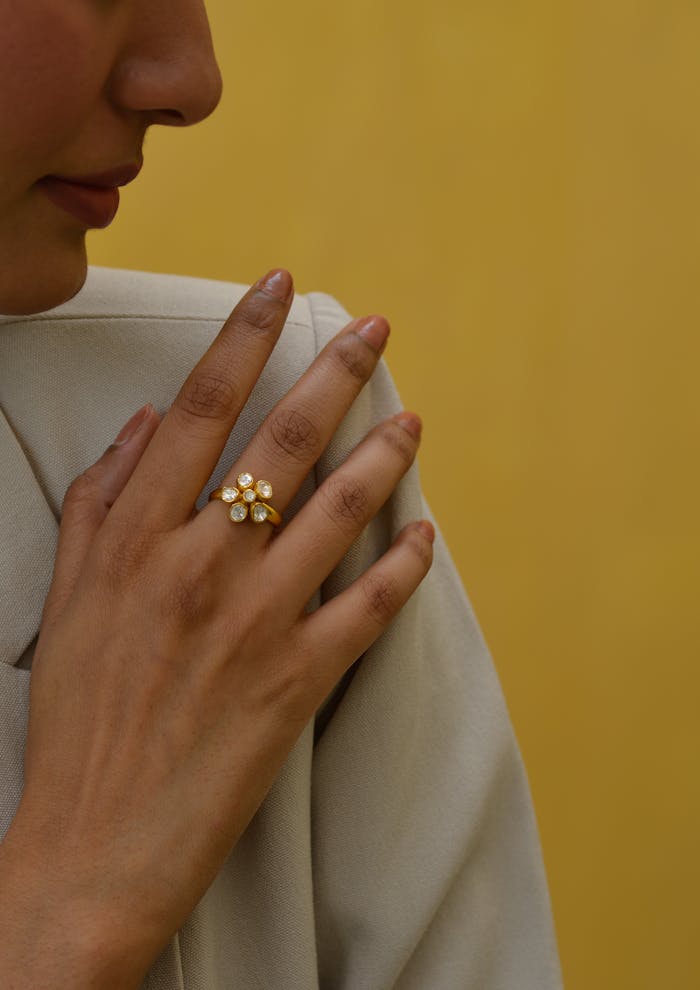 pexels-photo-17298618 Close-up of a floral ring on a woman's hand against a yellow background.